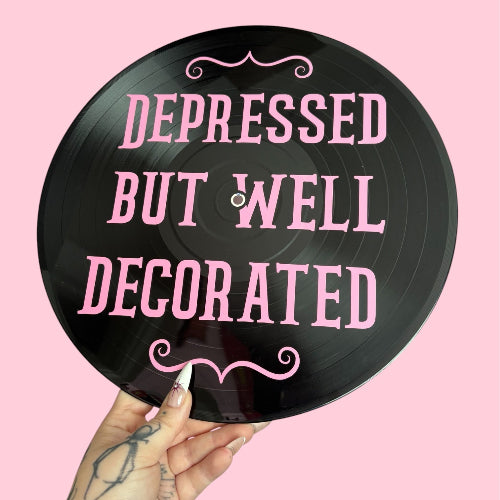 Vinyl record with 'Depressed But Well Decorated' text on a pink background